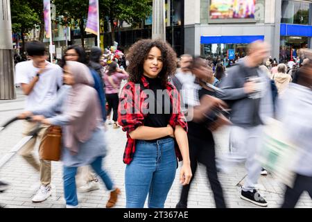 Smiling woman standing amidst crowd in city Stock Photo