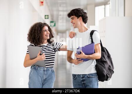 Smiling students talking in corridor Stock Photo