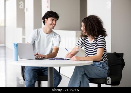 Smiling students talking at table in university Stock Photo
