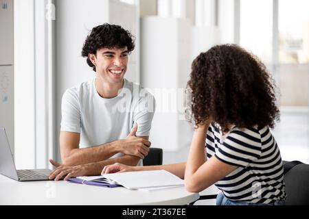 Smiling students communicating at table in university Stock Photo