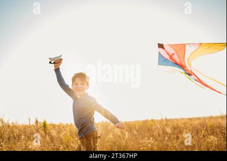 Smiling boy flying kite in field Stock Photo