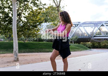 Woman using smart watch standing at park Stock Photo