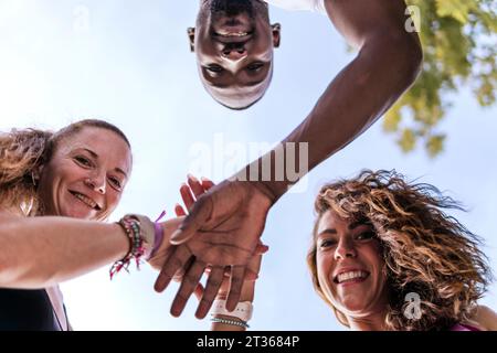 Happy multiracial friends stacking hands Stock Photo