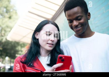 Happy young man with woman using smart phone Stock Photo