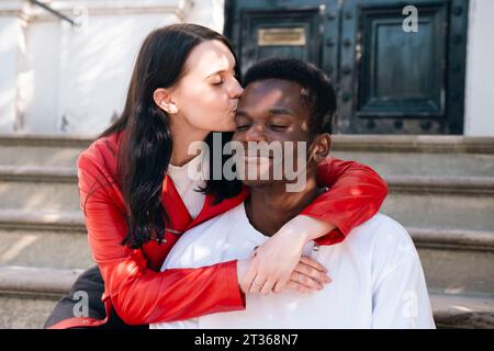 Young woman kissing man sitting on steps Stock Photo
