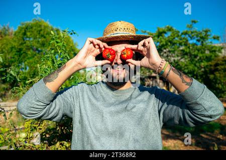 Playful horticulturist placing tomatoes on eyes Stock Photo