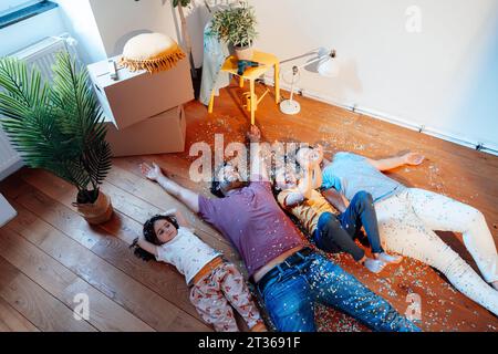 Happy family having fun with confetti and lying on floor at home Stock Photo