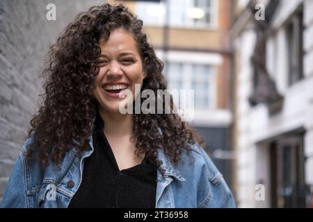 Cheerful young woman standing near buildings Stock Photo