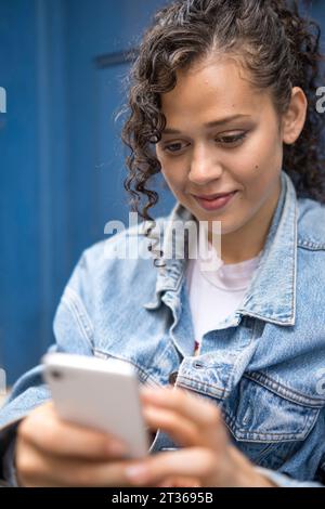 Smiling young woman using smart phone Stock Photo