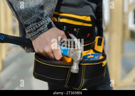 Engineer wearing tool belt holding hammer in hand Stock Photo