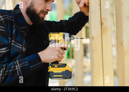 Blue-collar worker drilling wood at construction site Stock Photo