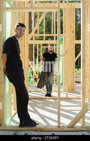 Blue-collar workers standing near construction frame on sunny day Stock Photo