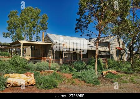 Abandoned cottage of corrugated iron and wood, with overgrown garden, in the former gold mining town of Kookynie, now a ghost town, Western Australia Stock Photo