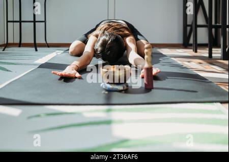 Woman practicing Balasana pose on yoga mat at home Stock Photo