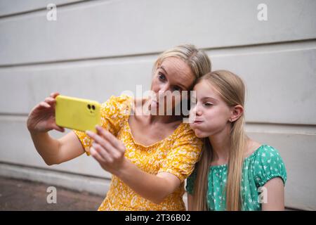 Mother and daughter making faces and taking selfie on smart phone Stock Photo