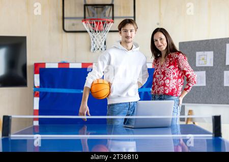 Smiling young trainee standing with businesswoman in office Stock Photo