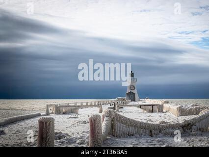 thick Ice formations over the guard rails in the pier. Winter  landscape on the lake with lighthouse and stormy sky, winter wonderland Stock Photo