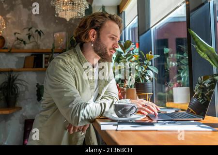 Young businessman working on laptop at cafe Stock Photo