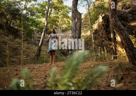 Teenage girl with hands clasped standing in forest Stock Photo