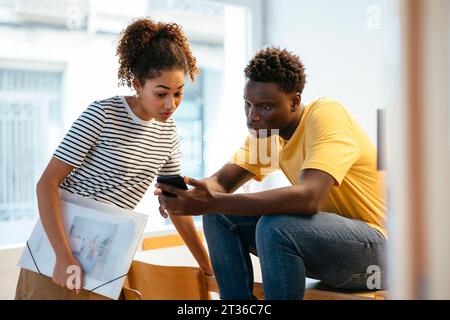 Young students using smart phone and discussing at university Stock Photo