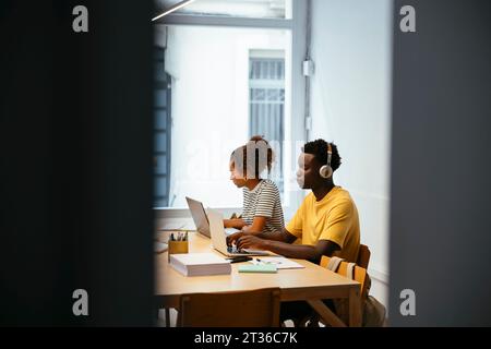 Young students studying and using laptop at desk Stock Photo