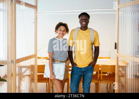 Happy young students standing together in doorway at university Stock Photo