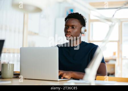 Young student with wireless headphones using laptop at university Stock Photo