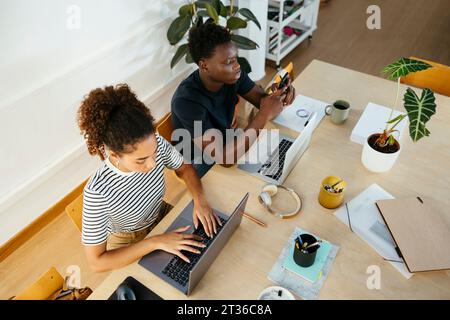 Young students using laptop and smart phone at desk Stock Photo