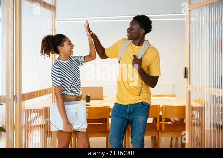 Students giving high-five to each other in doorway at university Stock Photo