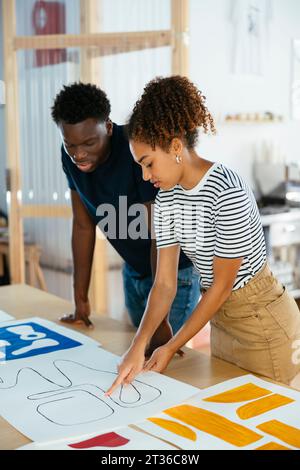 Young student discussing with friend over art on desk at university Stock Photo
