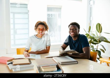 Happy students with books studying in library Stock Photo