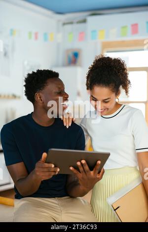 Happy young students using tablet PC together at university Stock Photo