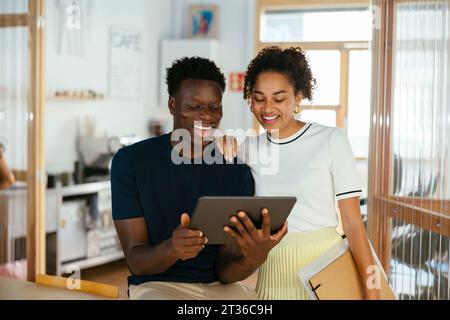 Happy students using tablet PC together at university Stock Photo