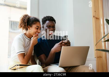 Happy student with friend using mobile phone at university Stock Photo