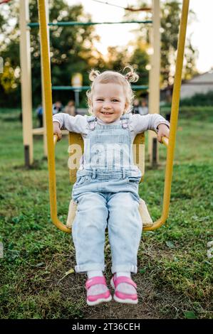 Smiling girl sitting on swing in park Stock Photo