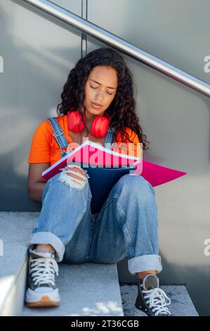 Young student sitting on steps and studying in campus Stock Photo