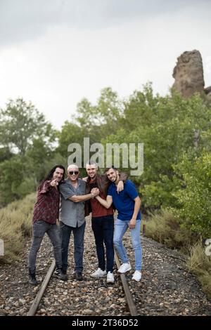 Happy friends standing on railroad tracks amidst plants Stock Photo