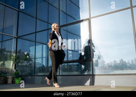 Businesswoman talking over smart phone and walking on terrace Stock Photo