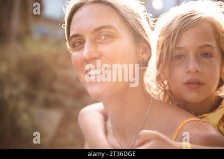 Smiling mother giving piggyback ride to son Stock Photo