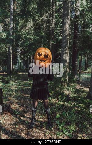 Woman wearing Jack O' Lantern standing in forest Stock Photo