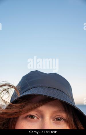 Young woman wearing bucket hat under sky Stock Photo