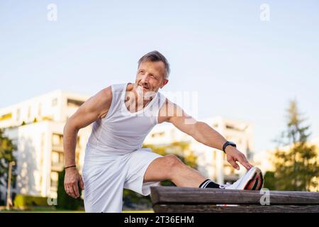 Sportsman doing stretching exercise in park Stock Photo