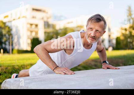 Mature man doing push-ups in park Stock Photo