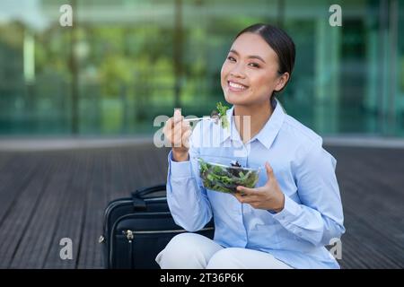 Young asian office worker lady having lunch sitting outdoors Stock Photo