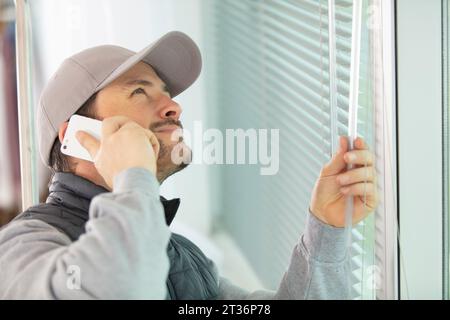 worker in uniform installing blinds on plastic upvc window Stock Photo