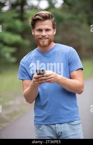 bearded man outdoors using a smartphone Stock Photo