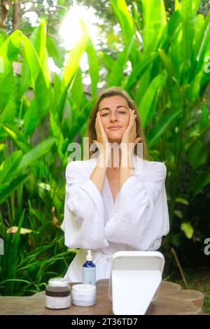 Medium shot of a middle-aged woman applying anti-aging cream under eyes Stock Photo
