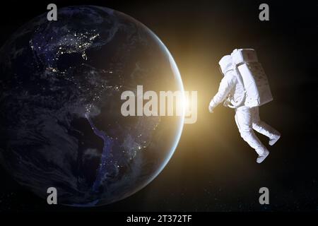 Astronaut in deep space looks on night Earth planet. Elements of this image furnished by NASA. Stock Photo