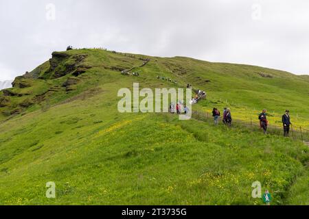 Skogafoss, Iceland - July 8, 2023: Tourists begin their climb up the stairs to see Skogafoss waterfall from the top viewpoint Stock Photo