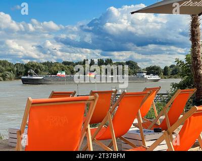 View over orange deckchairs in the sand from beach bar on river Rhine, Rheinfeld, Dormagen, North Rhine-Westphalia, Germany Stock Photo